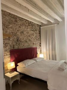 a bedroom with two beds and a brick wall at Venetian Apartments in Venice