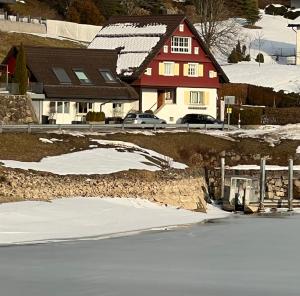 a house with a lot of snow in front of a lake at Hermitage Sihlsee in EGG