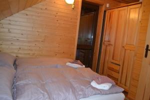 sypialnia z łóżkiem w drewnianej ścianie w obiekcie Chata Simon w mieście Nižná Boca