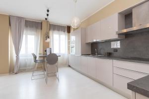 uma cozinha com armários brancos e uma mesa e cadeiras em Appartamento Ospedale Civile 5 - F&L Apartment em Brescia