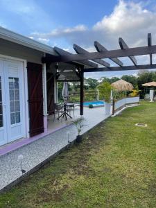 a house with a pavilion with a table and a patio at Palmier bungalow- piscine in Gros-Morne