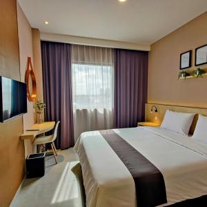 a hotel room with a large bed and a desk at The Mango Suites by Flat06 in Jakarta