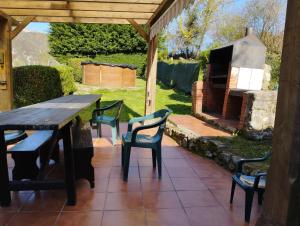 un patio con mesa, sillas y chimenea en LA NOZAL (piscina, barbacoa, jardín...), en Llanes