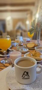 una mesa con una taza de café y un vaso de zumo de naranja en Posada Aitue en Villa General Belgrano