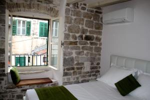 ein Schlafzimmer mit einer Steinmauer, einem Bett und einem Fenster in der Unterkunft Luxury San Giovanni Apartment 2 in Split