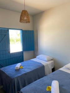 a bedroom with two beds with towels and a window at Pousada Vila Lua Bela in Pitimbu