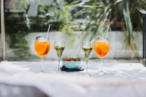 three glasses of wine and a bowl of flowers on a table at Hôtel La Villa Cannes in Cannes