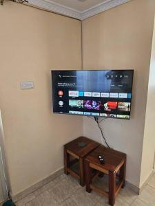 uma televisão de ecrã plano pendurada numa parede com uma mesa em The Barn Entire 3 Bed House Self catering em Ruaka