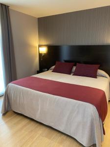 una habitación de hotel con una cama grande con almohadas rojas en Petit Palau - Adults Only, en Blanes