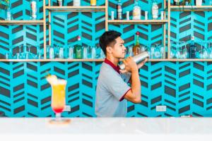 a young man standing at a bar with a drink at Triple L Hotel Patong Beach Phuket in Patong Beach