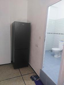 a black refrigerator in a bathroom with a toilet at Studio Meknes Hamria in Meknès