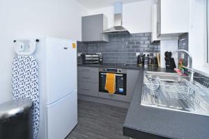 uma cozinha com um frigorífico branco e um lavatório em Find a touch of inspiration in this professional interior designers home! em Crewe