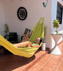 una mujer acostada en una hamaca leyendo un libro en Casa en la playa, en Santa Elena