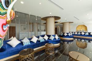 a lobby with a blue couch and some tables and chairs at Triple L Hotel Patong Beach Phuket in Patong Beach