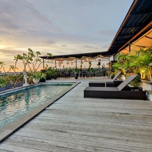 a resort with a swimming pool and a wooden deck at The Mango Suites by Flat06 in Jakarta