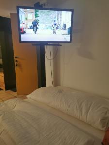 TV a schermo piatto appesa a un muro accanto a un letto di Studio Mario ad Alberschwende