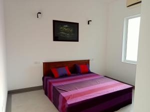 a bedroom with a bed with purple and red pillows at Nilwala Gate wetland Stay in Matara