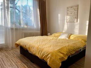 - une chambre avec un lit doté d'une couette jaune et d'une fenêtre dans l'établissement Apartment city centrum, à Nitra