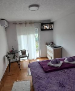 トレビニェにあるApartman Kristinaのベッドルーム(紫色のベッド1台、テーブル付)