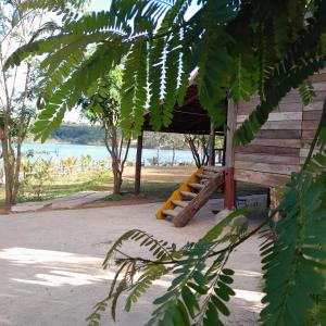 una cabina in legno sulla spiaggia con alberi e acqua di An Homestay a Di Linh