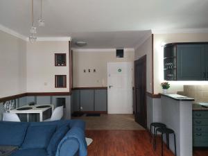 een woonkamer met een blauwe bank en een keuken bij Apartament Radosna in Gdynia