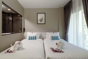 two beds with stuffed animals on them in a bedroom at Triple L Hotel Patong Beach Phuket in Patong Beach