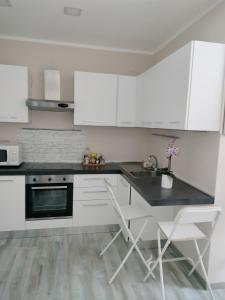 cocina con armarios blancos, mesa y sillas en Residence Villa Alba room nr 415, en Gardone Riviera