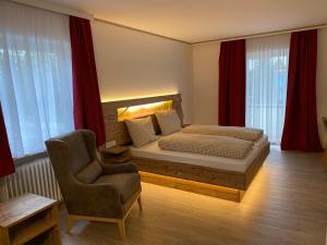 een slaapkamer met een bed en een stoel bij Hotel-Landgasthof Ploss in Schönwald