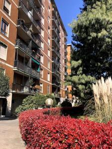 un gran edificio de apartamentos con un jardín de flores rojas en Appartamento Veronica, per lavoro e relax en Corsico