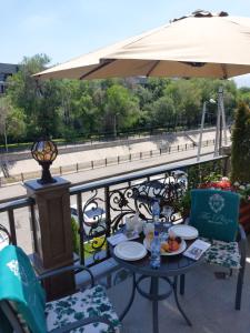 a table with plates of food and an umbrella on a balcony at Plaza Hotel Almaty in Almaty