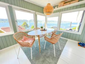 una mesa y sillas en una habitación con ventanas en Summer cabin by the sea Holmsbu. (40 min from Oslo) en Asker