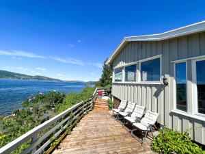 uma casa com cadeiras num passadiço de madeira junto à água em Summer cabin by the sea Holmsbu. (40 min from Oslo) em Asker