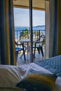 a bedroom with a view of a balcony with a table and chairs at Anglade Hotel in Le Lavandou