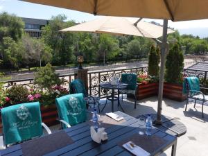 a patio with tables and chairs and an umbrella at Plaza Hotel Almaty in Almaty