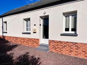 a white house with two windows and a brick wall at La Romance in Fressenneville