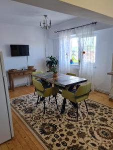 a dining room with a wooden table and green chairs at Apartament Central in Gherla