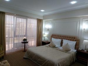 a bedroom with a large bed with white sheets and pillows at Plaza Hotel Almaty in Almaty
