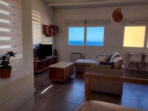 ein Wohnzimmer mit einem Sofa und einem TV in der Unterkunft Ático en Las Canteras in Las Palmas de Gran Canaria