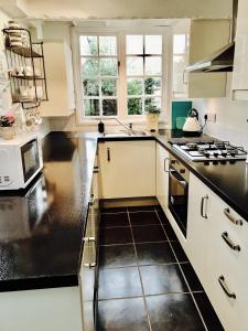 uma cozinha com armários brancos e bancadas pretas em Delightful Seaside Binnacle Cottage -hosted by Whitstable-Holidays em Whitstable