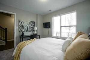 - une chambre avec un grand lit blanc et une fenêtre dans l'établissement Glam & Silver Home near Convention Ctr, à Indianapolis