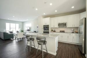 a kitchen with white cabinets and a kitchen island with bar stools at Glam & Silver Home near Convention Ctr in Indianapolis