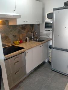 una cucina con armadi bianchi e frigorifero in acciaio inossidabile di MIRAMAR 32 a San Isidro