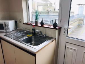 a kitchen with a sink and a microwave and a window at Lovely 3 bedroom apartment in Buncrana in Buncrana