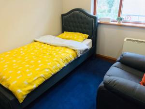 1 dormitorio con cama con sábanas amarillas y sofá en Lovely 3 bedroom apartment in Buncrana, en Buncrana