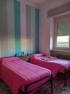 2 Betten in einem Zimmer mit rosa Bettwäsche und einem Fenster in der Unterkunft B&B delle Arti in Crema