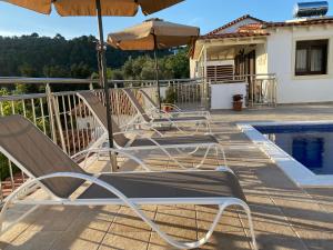 two chairs and an umbrella next to a swimming pool at Villa Valmas Private Escape in Skiathos