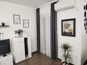 a living room with white walls and a tv at Apartman 007 in Kragujevac