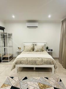 a white bedroom with a bed and a tv at Sweet Home Alibama in Nelspruit