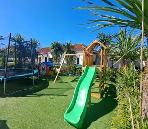 a playground with a green slide in a yard at Centenária in Oiã