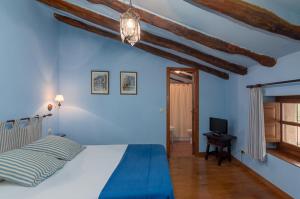 a blue bedroom with a bed and a television at Casona De La Salceda in Treceño